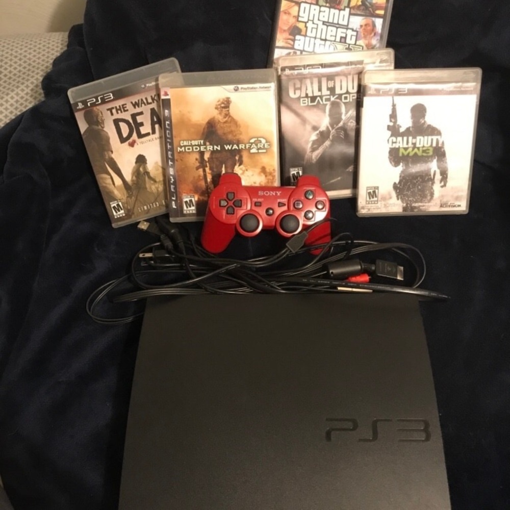 Red sony ps3 slim console with controller and game